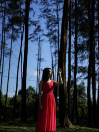 Rear view of woman standing on field in forest