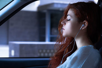 Side view of woman listening music while sitting in car