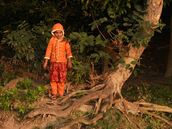 Full length of young woman standing in forest