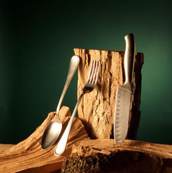 Close-up of knife and eating utensil on woods against green background