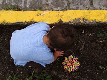 High angle view of boy with toy playing in mud at yard