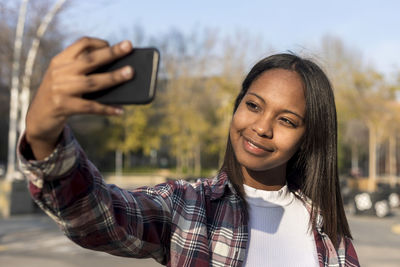 Young woman taking selfie while standing outdoors 