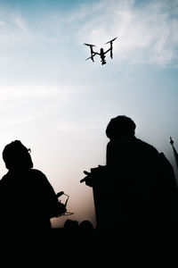Low angle view of silhouette people against sky