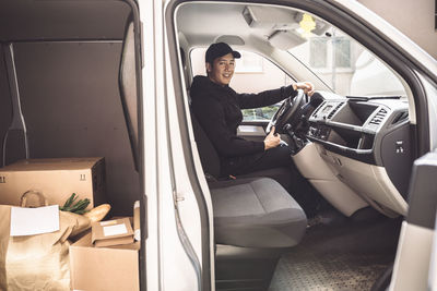 Portrait of smiling driver with package sitting in truck