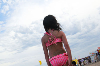 Rear view of girl in bikini standing against sky