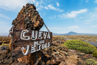 Information sign hanging on rock against sky at lanzarote island
