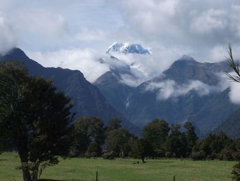 Scenic view of grassy field and mountains against sky