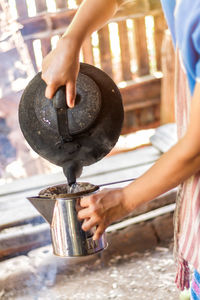 Close-up of woman pouring coffee in cup