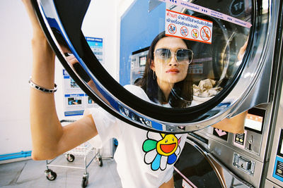 Portrait of woman standing with reflection in mirror