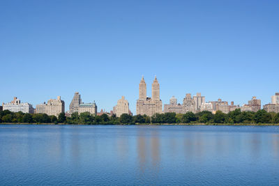 City at waterfront against blue sky