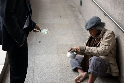 Beggar sitting on street in city