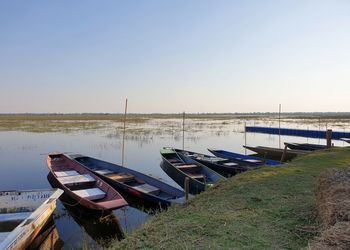 Boats moored in lake against clear sky