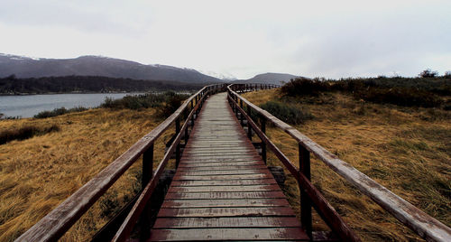 Boardwalk leading towards mountain against sky