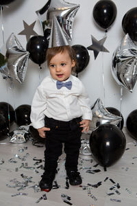 Boy in black clothes on his birthday party with balloon and silver stars