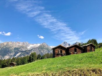 House on field by mountain against sky