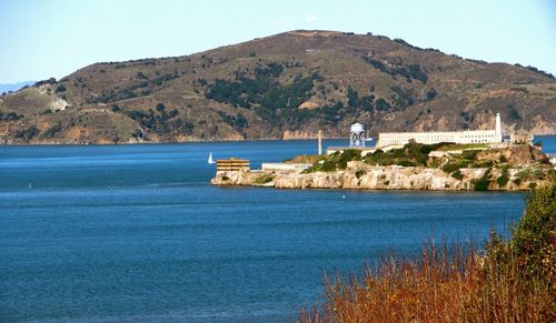 Alcatraz island amidst river in front of mountains