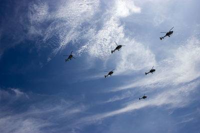 Low angle view of helicopters flying against sky