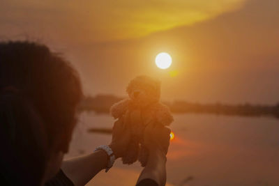 Full length of man holding woman against sky during sunset