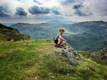 View of boy sitting on mountain