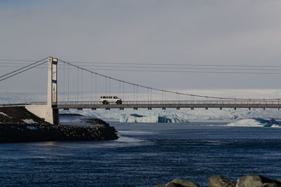 Low section of woman standing on bridge over river against sky