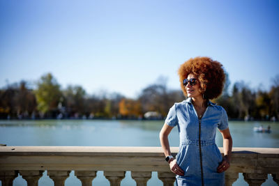 Young woman wearing sunglasses standing against sky