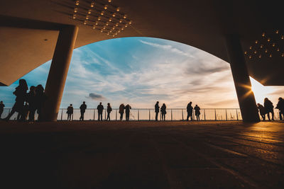 Silhouette people walking against sky during sunset