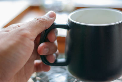 Close-up of hand holding coffee cup