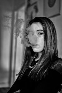 Portrait of woman exhaling smoke at home