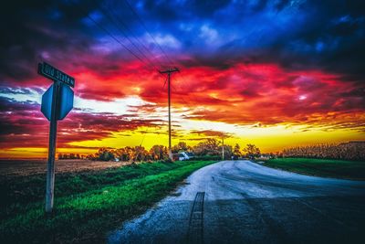 Road amidst field against sky during sunset