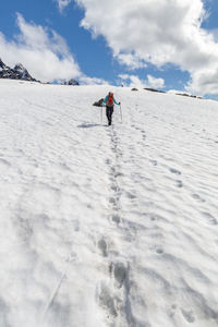 Rear view of person hiking on snowcapped mountain