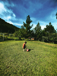 Rear view of woman sitting on grassy field