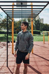 Young man bodybuilder having break during his workout in a modern calisthenics street workout park