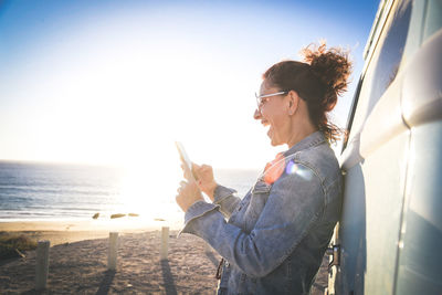 Woman using phone while standing at beach