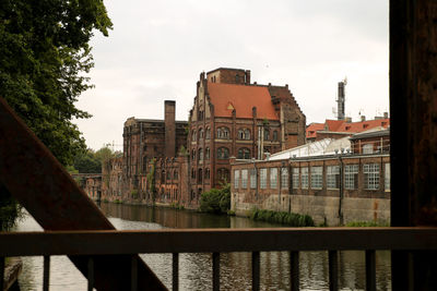 Buildings by canal against sky in city