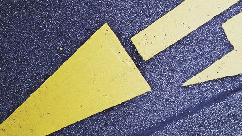 Close-up of yellow arrow symbol on road