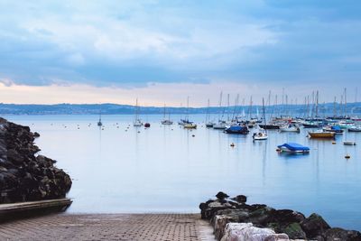 Sailboats moored on sea against sky