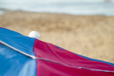 Close-up of red umbrella on beach