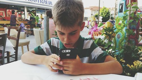 Boy using mobile phone at cafe