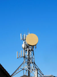 Low angle view of communications tower against clear blue sky