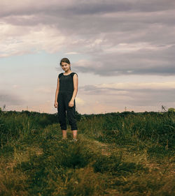 Full length of girl standing on field against sky