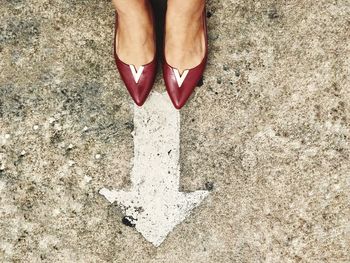 Low section of woman standing by arrow symbol on street