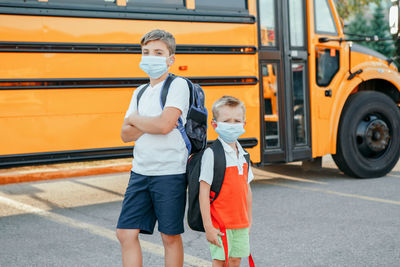 Boys wearing mask standing on bus