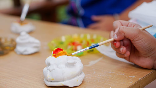 Midsection of person holding ice cream on table