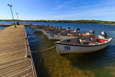 Boats moored on pier by sea against sky