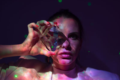 Woman holding crystal against violet background