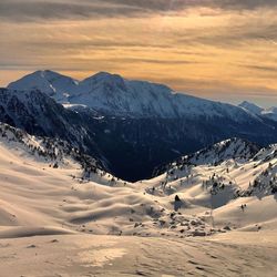 Scenic view of snowcapped mountains against sky during sunset