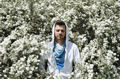 Man standing amidst white flowers on sunny day