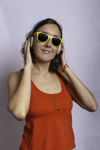 Portrait of woman wearing sunglasses standing against gray background