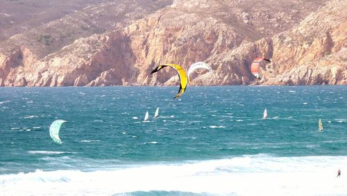 Parachutes over sea by mountain