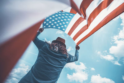 Low angle view of person holding flag against sky